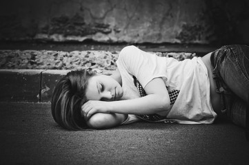 Portrait of sleeping young girl on asphalt. Black and white