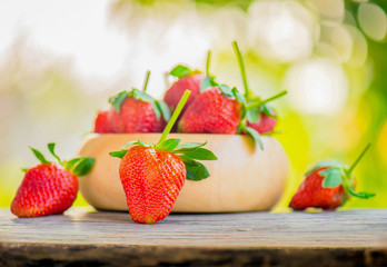 Strawberry in the wooden bowl on the green blured background