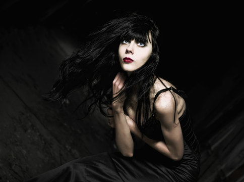 Portrait of beautiful goth girl among the dark