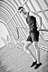 Fashion shot: handsome young man stands on staircase. Black and white