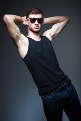 Studio fashion shot: handsome young man wearing jeans, shirt and sunglasses