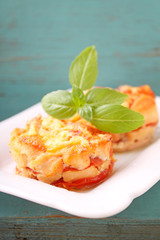 chicken baked with tomatoes and cheese in a white plate on a blue background