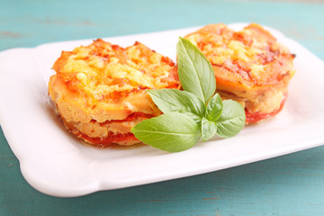 chicken baked with tomatoes and cheese in a white plate on a blue background