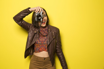 Fashion young girl makes the photo with old camera. Yellow backg
