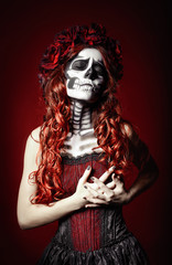 Sad young woman with muertos makeup (sugar skull) holding her chest