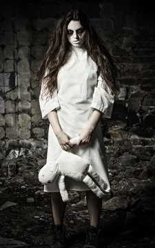 Horror style shot: scary monster girl with moppet doll in hands