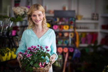 Happy female florist holding basket of flowers