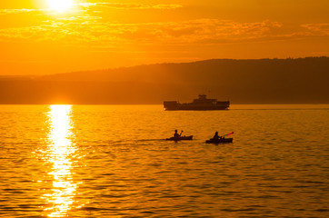 Naklejka premium Kayakers and Ferry on Lake Superior at Sunset