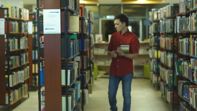 student boy walking and chooses of a book in the library