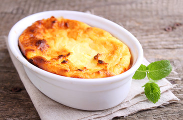 Cottage cheese casserole in white dish, on a blue background
