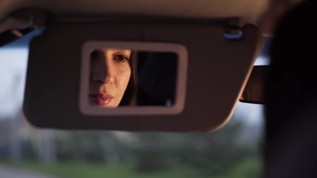 Woman applies makeup in the car