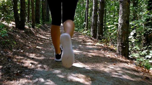 Tracking camera of woman girl running jogging in park, wood, forest, slow motion