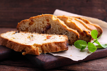 a piece of cake with raisins and candied fruit on a white plate on a blue background