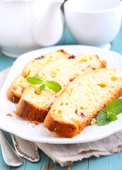 a piece of cake with raisins and candied fruit on a white plate on a blue background
