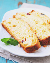 a piece of cake with raisins and candied fruit on a white plate on a blue background