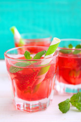 strawberry drink with mint in a glass beaker on a turquoise background