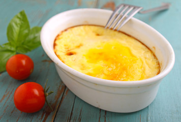 scrambled eggs baked in white on a dark wooden background