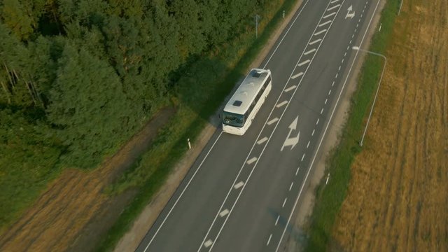 Aerial Shot of Tourist Bus Driving on Highway Surrounder by Forest