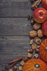 Wooden background with pumpkin, apples, nuts and spices.