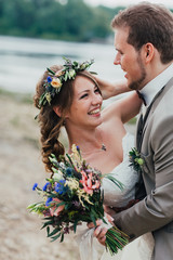 young groom and bride standing hugging on the background of the river