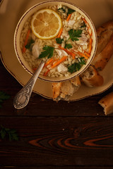 Chicken soup with pasta on a dark wooden background.