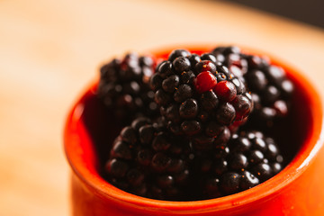 Blackberries in a cup on  blurred background of wooden planks