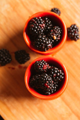 Blackberries in a cup on blurred background of wooden planks