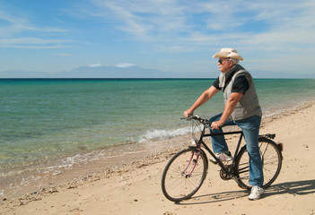 Obraz premium Man riding his bike along the beach in a sunny day