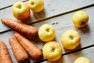 Top view of carrots and apples lying on a wooden table closeup