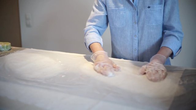 Девушка размыливает пену на заготовке во время валяния шерсти при работе над войлочным изделием