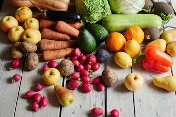 Set of ripe healthy foods consisting of vegetables and fruits lying on the wooden table closeup