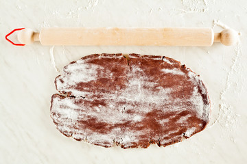 chocolate dough and rolling pin on a white marble table
