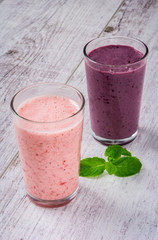 smoothie of strawberries and blackberry and mint leaves on a white wooden table