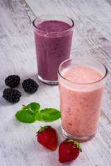 smoothie of strawberries and blackberry , strawberries, blackberry and mint leaves on a white wooden table