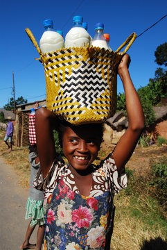 Young african girl carrying milk