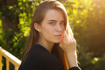 Young woman on the background of trees and sunlight 