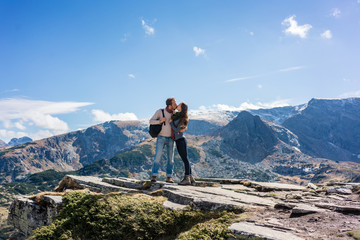 Frau und Mann küssen sich verliebt im Gebirge beim Wandern