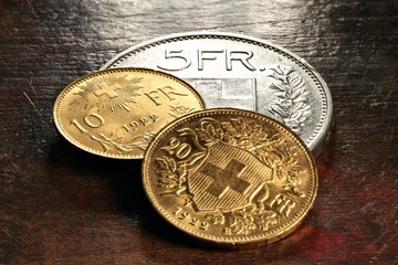Schweizer Silber- und Goldmünzen auf rustikalem Holztisch