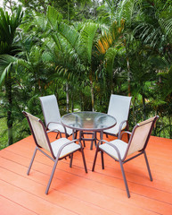 Table and chairs on the veranda in a tropical garden
