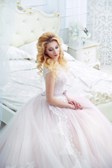Elegant Bride blonde in a long lace dress in the boudoir.