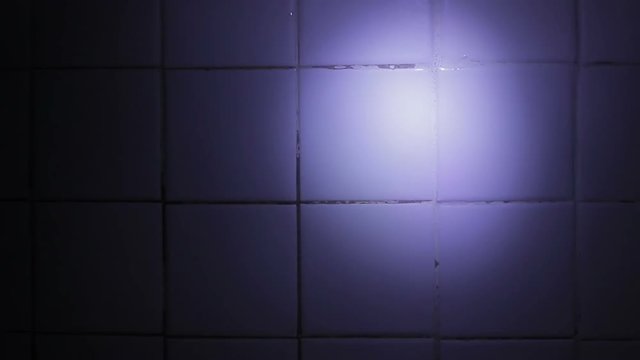 Light flashlight on the wall of tiles