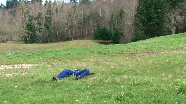 Bad guy in field in stand off with camera loses battle by getting shot, falling dead.