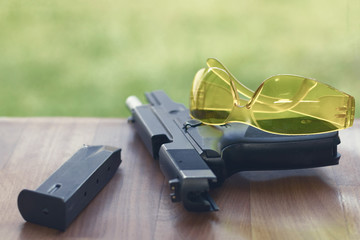 Handgun with safety glasses on a wooden background.