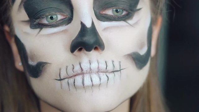 Close up of apply make-up the girl in the form of skull