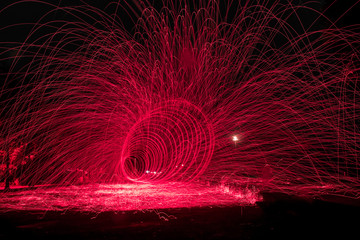 Showers of hot glowing sparks from spinning steel wool.
