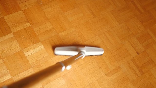 Closeup of a vacuum brush cleaning some wooden floor.