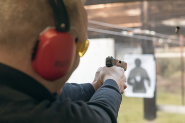 Shooting with a pistol. Man aiming pistol in shooting range. - obrazy, fototapety, plakaty