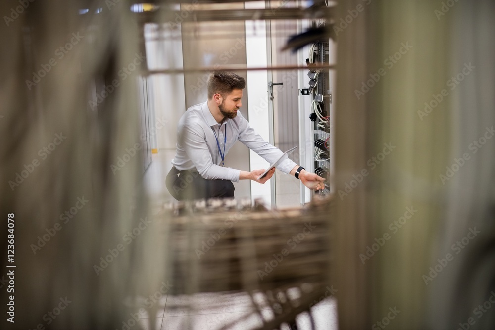 Poster Technician using digital tablet while analyzing server