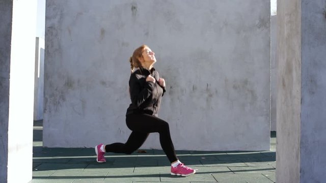 Attractive fitness woman doing lunges changing the feet in a jump on the sport ground