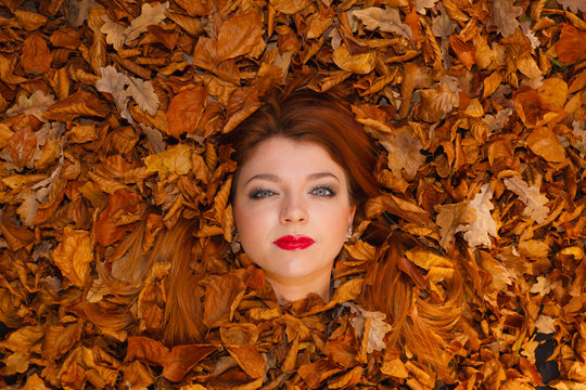 Young woman covered by leaves.